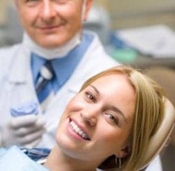 Woman smiling in the dental chair with her dentist behind her