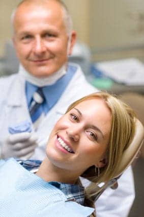 Woman smiling in the dental chair with her dentist behind her
