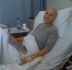 a cancer patient in a hospital bed smiling with a magazine on her lap